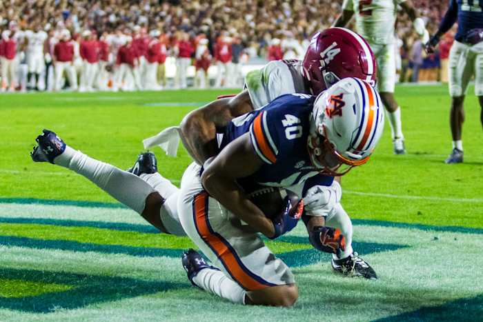 Auburn tight end Landen King (40) makes a one-handed grab to score a touchdown despite Alabama defensive back Brian Branch (14) holding his left arm during the first overtime of an NCAA college football game, Saturday, Nov. 27, 2021, in Auburn, Ala. The touchdown sent the game to a second overtime, a game won in four overtimes by Alabama, 24-22.